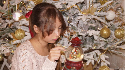 beautiful girl with snow globe under the xhristmas tree. High quality photo