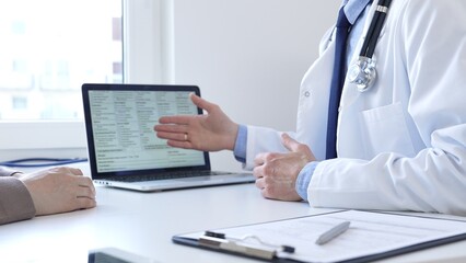 Doctor reviewing digital test results with patient, discussing health findings on laptop screen during clinical consultation. Medicine and health care concept.