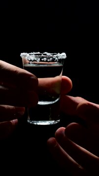 Shot of tequila and salt on a black background in the hands of a person.
A man drinks an alcoholic drink at a bar.
Mexican silver tequila close-up.
A shot glass with an alcoholic cocktail