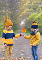 cute boy giving a colorful autumn leaf with a heart inside to a girl 