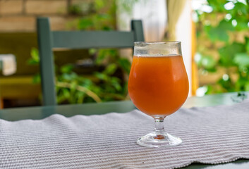 A glass of cold, of amber, bubbly, traditional kvass on a table outdoors. Refreshing fermented rye...