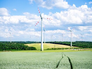 Wind turbines on a green field under a blue sky.
