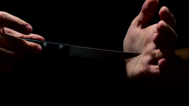 Robber with a knife in a black room preparing to attack.
Serial killer with a steel knife in his hands wants to rob someone.
Robber or criminal with a sharp knife in his hands at night