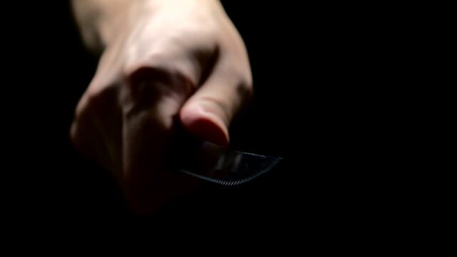 A man in black clothes threatens with a sharp steel knife in a conflict situation.
A man brandishes a sharp knife and intimidates someone.
A criminal with a knife
