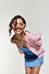 Beautiful woman in blue summer dress and stylish sunglasses posing playfully in studio
