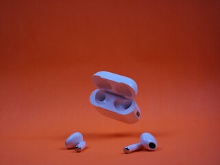 Modern Wireless Earbuds and Charging Case on Bright Orange Background