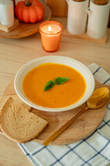 Plate of hot pumpkin soup and a slice of dark bread on the table. Warm autumn food. Immunity.