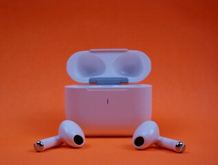 Modern Wireless Earbuds and Charging Case on Bright Orange Background