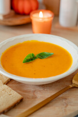 Plate of hot pumpkin soup and a slice of dark bread on the table. Warm autumn food. Immunity.