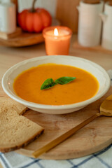 Plate of hot pumpkin soup and a slice of dark bread on the table. Warm autumn food. Immunity.