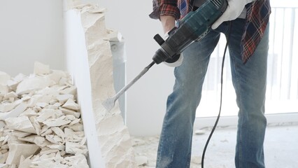 Unknown male construction worker wearing red checkered shirt jeans and protective gloves, is...