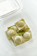 A Close-Up View of Freshly Made Ravioli Filled with Savory Ingredients, Showcasing Fine Culinary Craftsmanship in a Clear Container