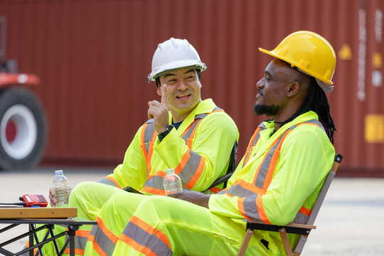 Workers Taking a Lunch Break at Industrial Port, Construction Workers on Break at Industrial Site, Diverse Male Laborers Resting Outdoors with Safety Gear