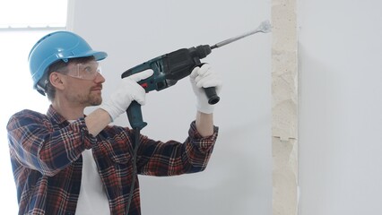 Male construction worker wearing red checkered shirt, blue protective helmet and gloves, is...