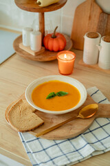 Plate of hot pumpkin soup and a slice of dark bread on the table. Warm autumn food. Immunity.