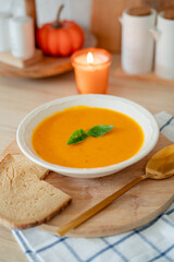Plate of hot pumpkin soup and a slice of dark bread on the table. Warm autumn food. Immunity.