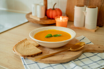 Plate of hot pumpkin soup and a slice of dark bread on the table. Warm autumn food. Immunity.