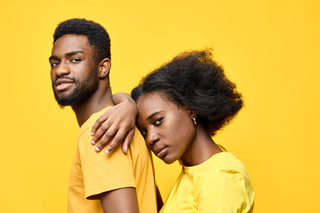 Fototapeta premium Close up portrait of a young Black couple wearing matching yellow clothing, showcasing love and connection against a vibrant yellow background