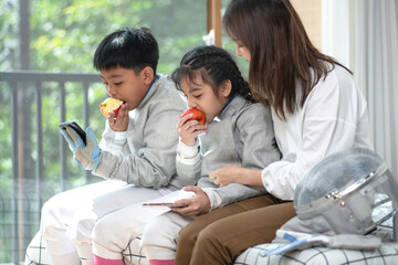 The fencer relaxes by spending time on his cell phone and eating an apple while his mother looks...