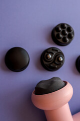 Pink massage gun with five black interchangeable heads arranged on purple background. Modern...