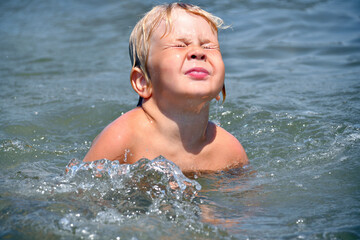 Little Boy Learning to Swim in the Sea on a Sunny Summer Day