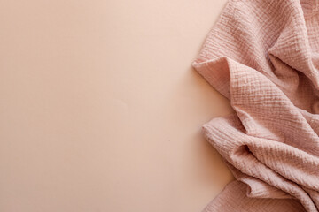 Textured pink muslin fabric softly draped on a pastel beige background. Delicate and minimal setup...