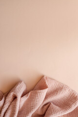Textured pink muslin fabric softly draped on a pastel beige background. Delicate and minimal setup...