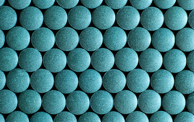Multiple blue round tablets arranged in geometric pattern. Dietary supplement and pharmaceutical medicine concept. Macro shot photography.