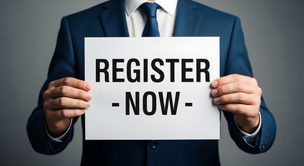 Obraz premium Businessman Holding Register Now Sign White Paper Blue Suit