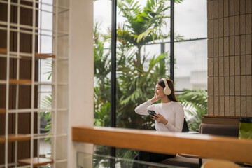 Young woman listening to music on headphones while relaxing in modern cafe