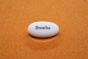 White oval stone with breathe text on orange sand image