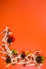 Autumn composition with pine cones, leaves, acorns and decorative ribbons on a bright orange...