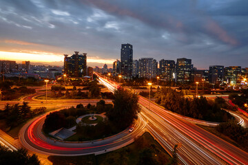 ​Beijing's Sanyuanqiao under twilight: Cityscape with neon-lit highways and streaks of car light...