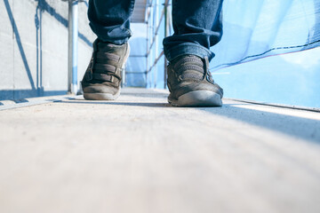 Engineer walking inside scaffolding with scaffold netting. Low angle view of female inspector,...