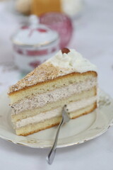 Slice of cake with whipped cream on top is sitting on a white plate
