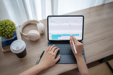 Businesswoman analyzing financial charts on tablet with stylus at home office desk