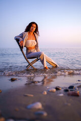 Young businesswoman enjoying a moment of freedom while sitting on a chair in the tranquil sea at...