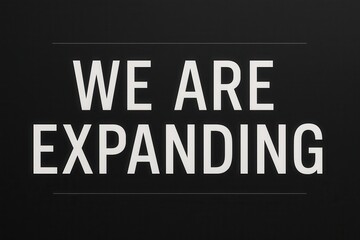 Bold white text on a black background stating "We Are Expanding," indicating business growth or company expansion, ideal for commercial or corporate use.