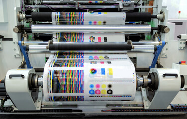 Large offset printing press or magazine running a long roll off paper in production line of industrial printer machine.