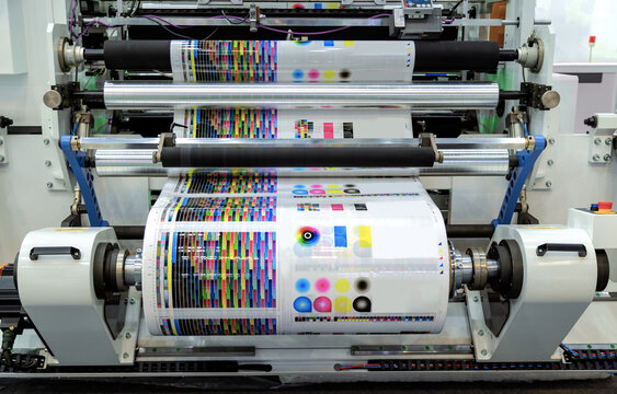 Large offset printing press or magazine running a long roll off paper in production line of industrial printer machine.
