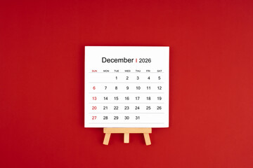 Calendar page for December 2026 with wood easel on a dark red background.