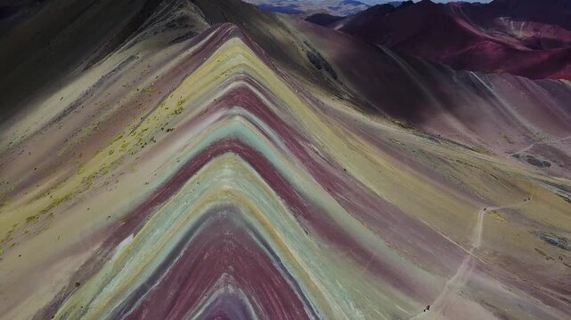 Aerial view of Rainbow Mountain showcasing vibrant layers of colorful sediment, creating a stunning geological tapestry, Cusco, Peru.