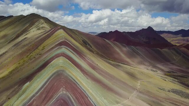 Aerial view of the vividly colorful Rainbow Mountain with stripes of red, yellow, and green cutting across the landscape, Cusco, Peru.