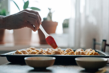 The process of making homemade cakes. Close-up of women's hands. A woman cooks a lot of pies with fillings in the kitchen at home.