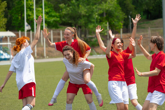 Female soccer players celebrate their teamwork on a sunny day outside. Concept of collective victory, energy and movement, dynamic moment in sports campaigns.