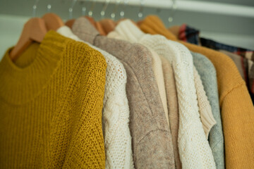 Warm autumn clothes knitted in the closet. Home organization.