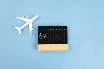 August 2026 black wooden calendar and airplane toy on blue color background.