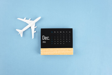 December 2026 black wooden calendar and airplane toy on blue color background.