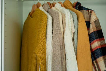 Warm autumn clothes knitted in the closet. Home organization.