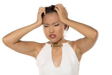 Kazakh woman holding head in frustration and stress, eyes closed, studio shot on white background.